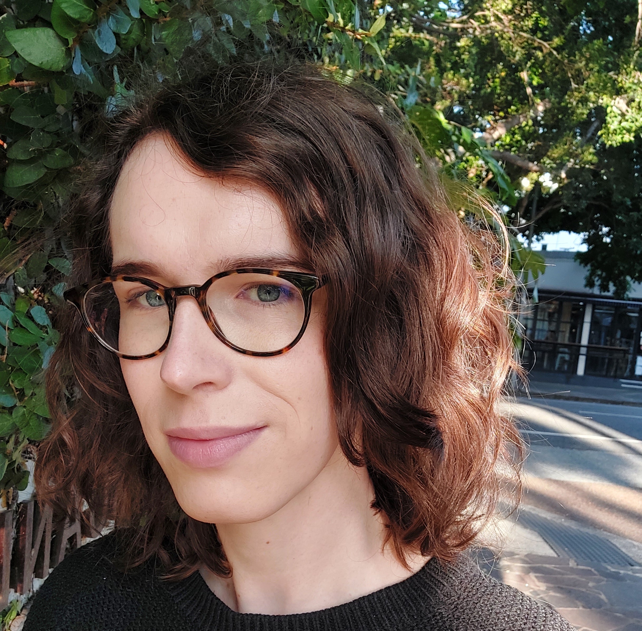 Photo of Dr Emily Kahl - a white woman with brown, curly hair, wearing thick-rimmed, tortoise shell glasses