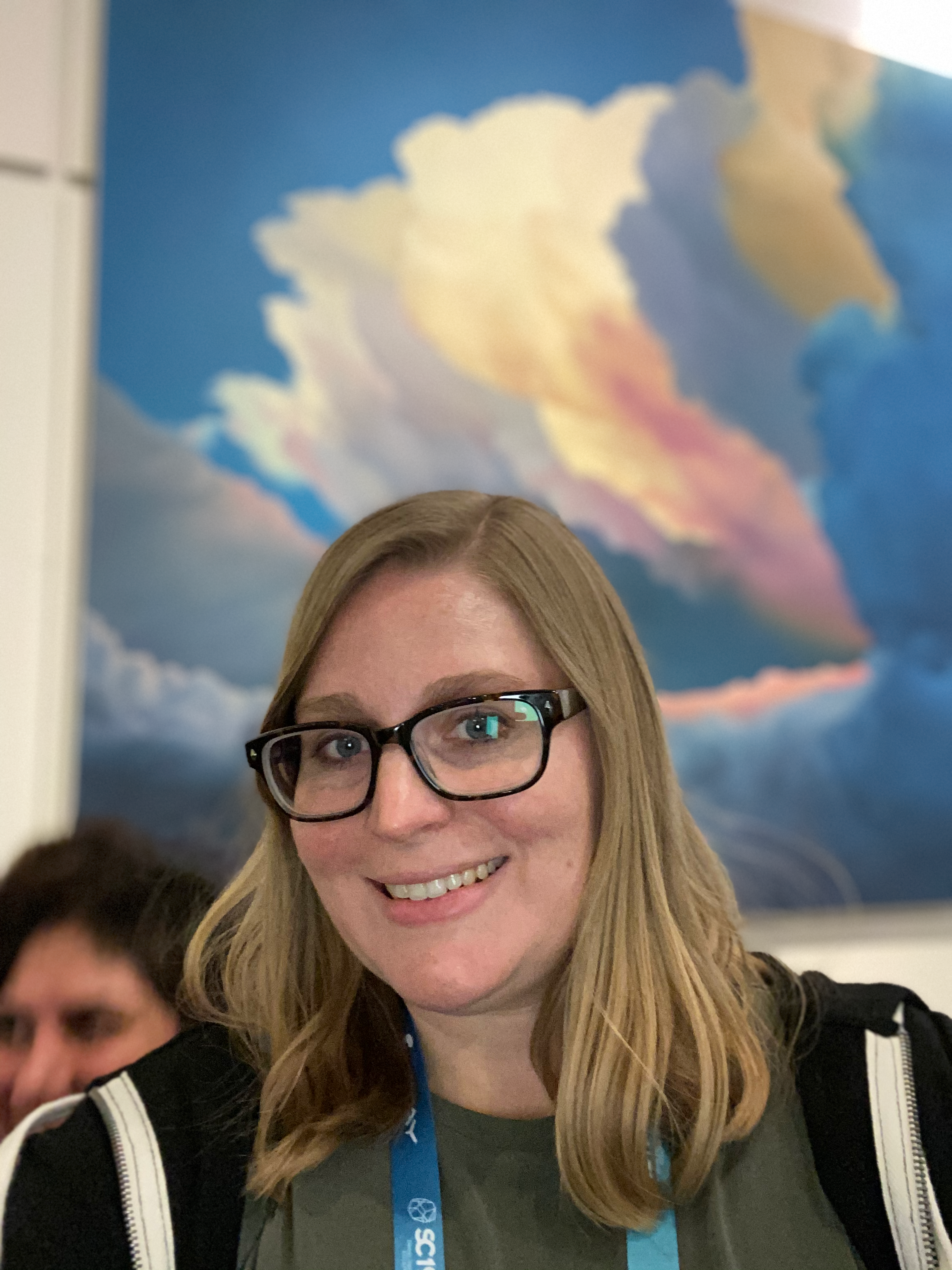 Headshot of Elsa Gonsiorowski in front of a painting of clouds.